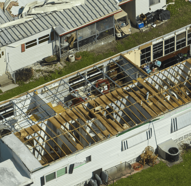 A damaged house with its roof partially removed, revealing the interior.
