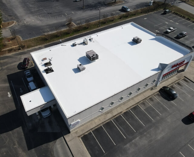 Aerial view of a white commercial building with parking spaces.