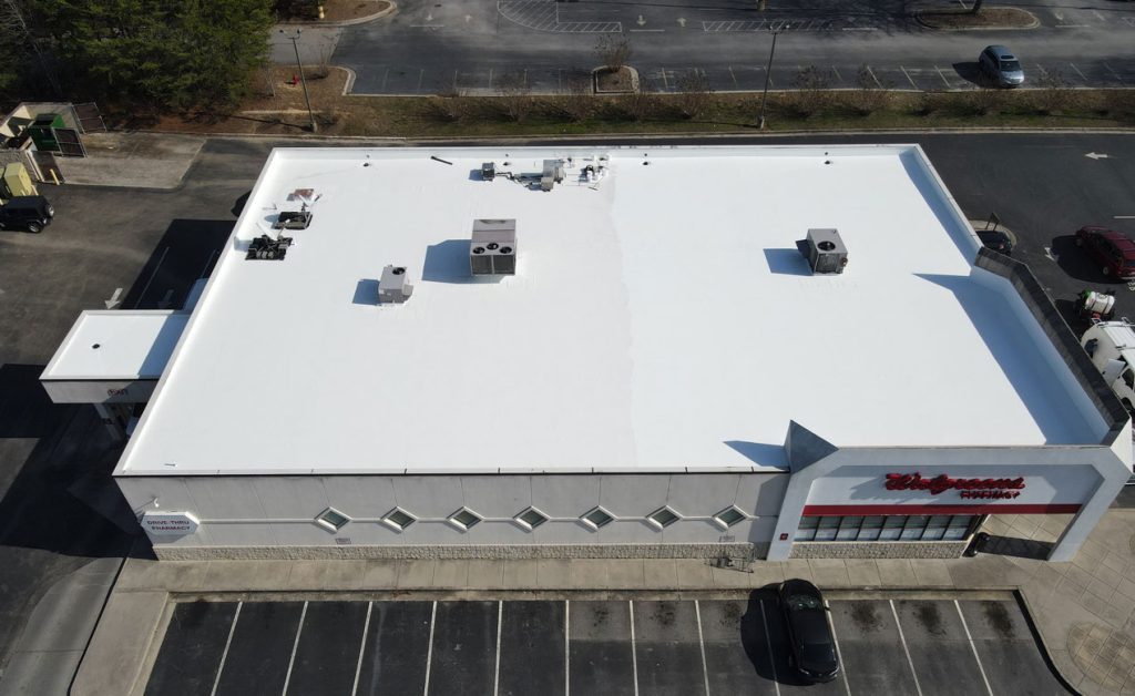 Aerial view of a large white-roofed commercial building with parking spaces.