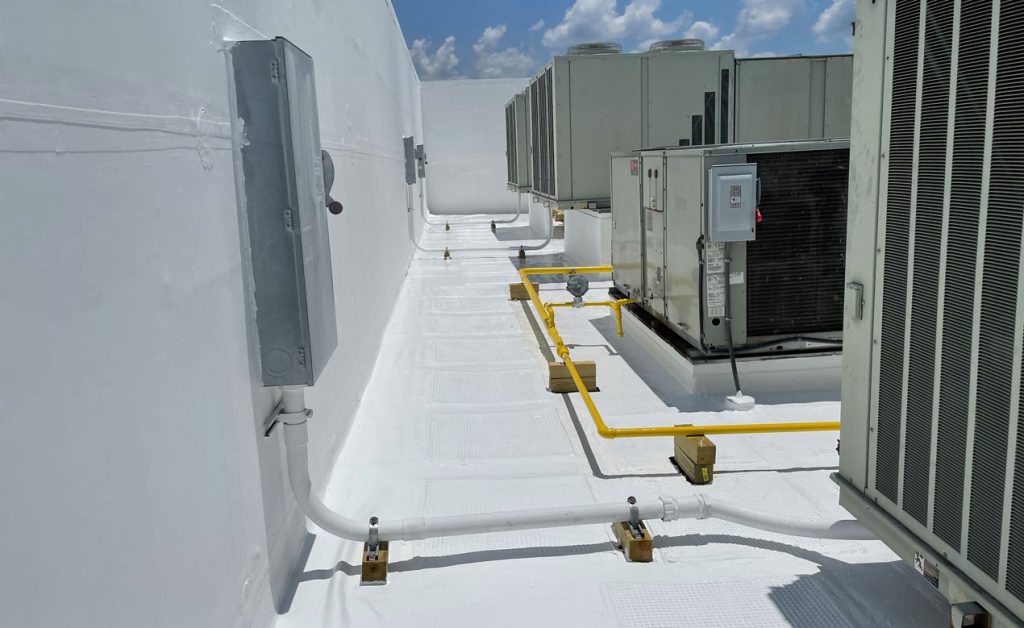 Rooftop HVAC system with yellow gas piping and electrical conduits under a partly cloudy sky.