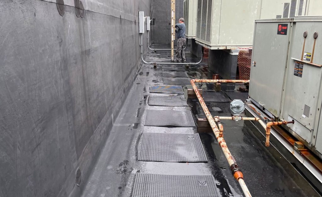 A rooftop with HVAC equipment and protective grates over cables.