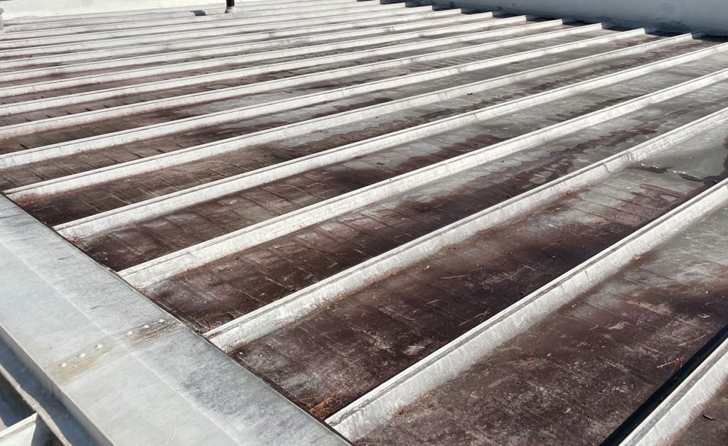 Close-up of a weathered metal roof with parallel ridges.