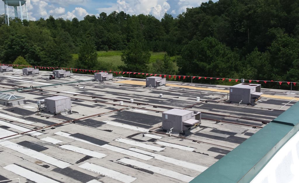 Flat commercial roof with HVAC units on a sunny day.